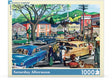 Box Cover of a colorful jigsaw puzzle featuring a lively 1950s town square scene with vintage General Motors cars and bustling shops by NY Puzzle Co