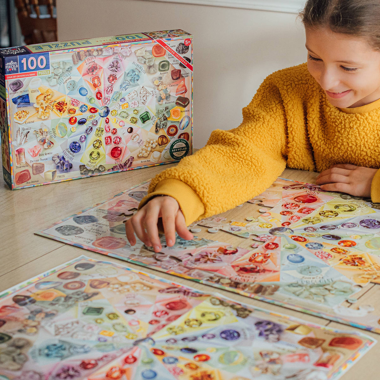 Putting together the puzzle showcasing gemstones and crystals with an informational poster included by eeBoo